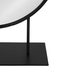 a round mirror sitting on top of a black stand