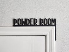 a sign that says powder room hanging on the side of a white door in front of a white wall