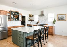 a kitchen with an island and chairs in the center, surrounded by wooden cabinets on both sides