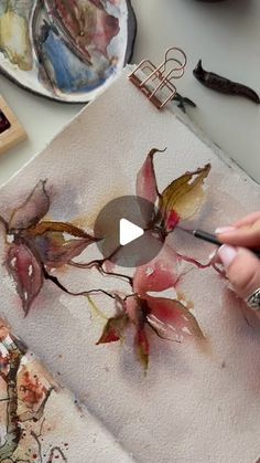 someone is painting flowers on a piece of paper