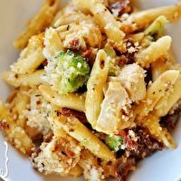 a white bowl filled with pasta and broccoli on top of a wooden table