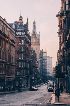 a city street with tall buildings and a clock tower