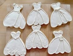 decorated cookies in the shape of wedding gowns on a cutting board with white icing