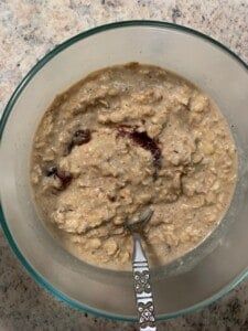 a bowl filled with oatmeal sitting on top of a counter next to a spoon