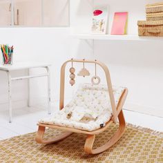 a child's rocking chair in a room with white walls and rugs on the floor