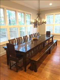 a dining room table and bench with windows in the background