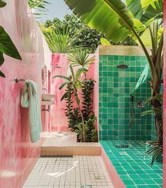 a bathroom with pink walls and green tiles on the shower wall, while palm trees are in the background