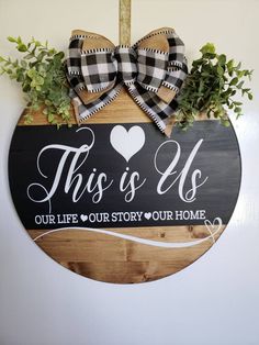 this is us our life story your home sign hanging on the wall with greenery