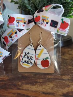 two pairs of wooden earrings with the words mr and mrs written on them in front of a potted plant