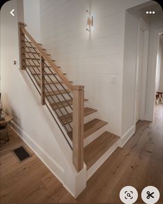 there is a wooden stair case in the house with white walls and wood floors on both sides