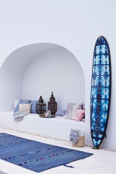 a blue and white surfboard sitting on top of a bench next to a rug