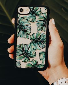 someone is holding up their phone case to show it's green leaf print on the back