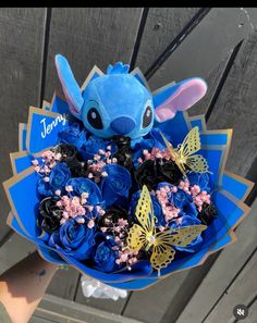 someone holding a bouquet of blue flowers with lillies and butterflies