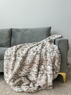 a couch with a blanket on top of it in front of a white wall and carpet