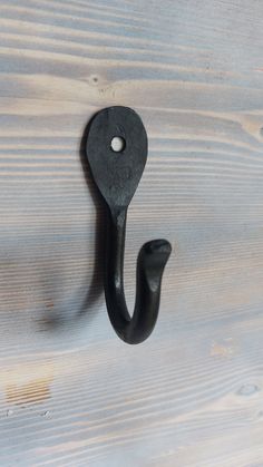 a black hook on the side of a wooden wall