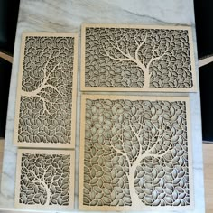 four laser cut panels with trees on them in various shapes and sizes, sitting on a marble slab