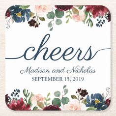 a coaster with flowers and the word cheers on it in blue, red, and pink