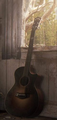 an acoustic guitar sitting in front of a window