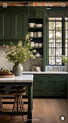 a kitchen with green cabinets and white counter tops, an island in front of the sink