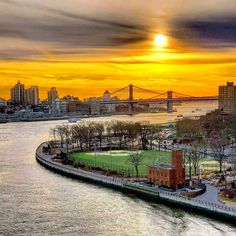 an aerial view of a city and the water at sunset with a bridge in the background