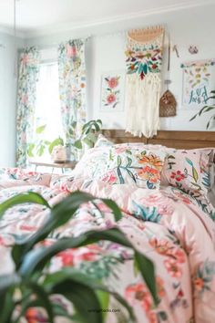 a bed with pink and green floral comforter in a bedroom next to a window