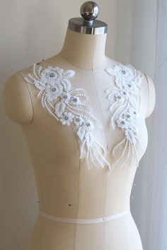 a mannequin with white beading and flowers on it