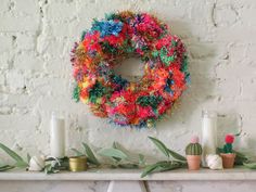 a wreath is hanging on the wall above a mantle with candles and other decorations around it