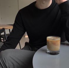 a man sitting at a table with a cup of coffee in front of his face