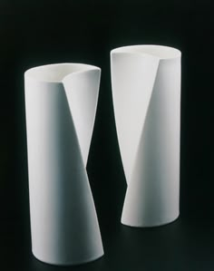 two white vases sitting side by side on a black surface