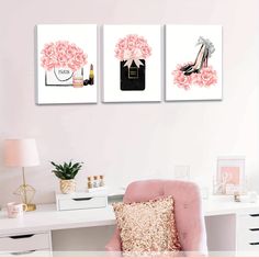 a pink chair sitting in front of two pictures on the wall next to a desk