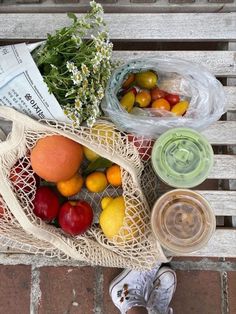 a bag full of fruit sitting on top of a wooden bench next to other fruits and vegetables