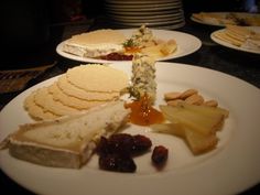 several plates with different types of food on them, including crackers and cheeses