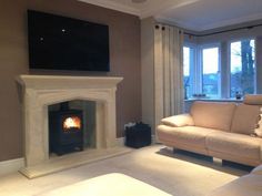 a living room with a couch, fireplace and television on the wall in front of it