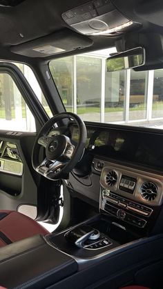 the interior of a vehicle with dashboard, steering wheel and dash board in front of large windows