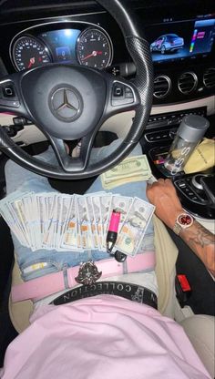 a person sitting in the driver's seat of a car with lots of money