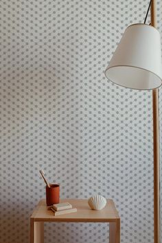 a small table with a lamp on it next to a wallpapered background that has wavy shapes