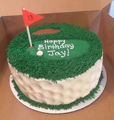 a birthday cake in the shape of a golf hole with a red flag on top