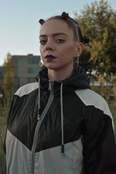 a woman standing in the grass with her mouth open and wearing large hoop earrings