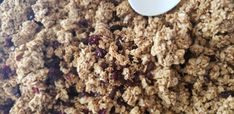 granola with raisins and cranberries in a bowl next to a spoon