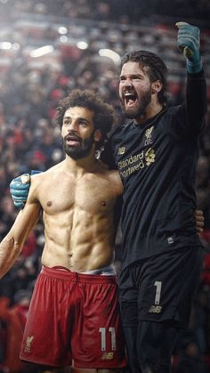 two men standing next to each other in front of a crowd at a soccer game