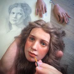 a woman is holding a pencil in her mouth and looking at the camera while she's drawing