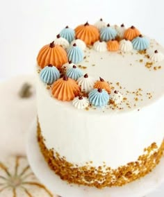 there is a white cake with orange and blue decorations on it