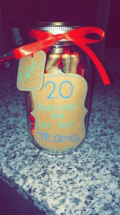 a jar filled with lots of candy sitting on top of a counter next to a red ribbon