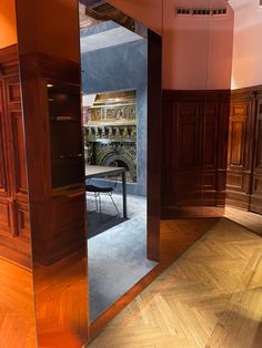 an empty room with wooden flooring and large mirrors on the wall, reflecting furniture in it