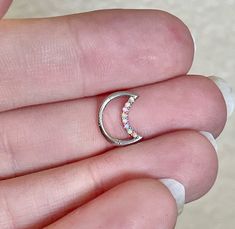 a person is holding a tiny crescent ring