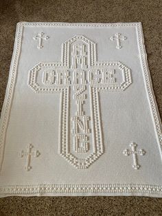 a white crocheted rug with a cross on it