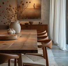 a wooden table topped with vases filled with flowers next to a painting on the wall