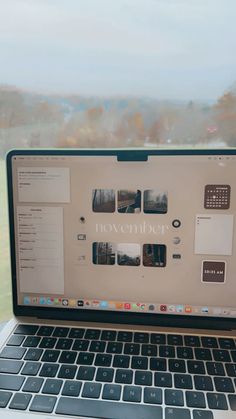 an open laptop computer sitting on top of a wooden table next to a glass window