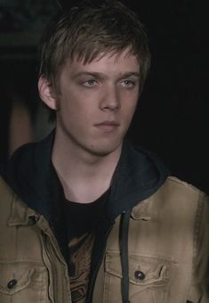 the young man is wearing a jacket and looking at the camera with an intense look on his face