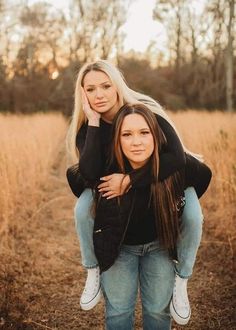 two young women are posing for a photo in the field with their arms around each other